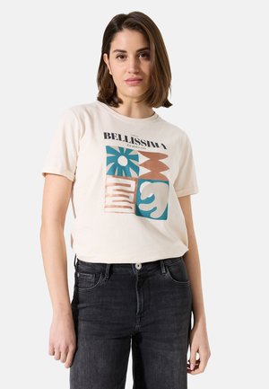 T-shirt en coton beige clair avec un design graphique comportant des motifs bleus, orange et marron. Manches courtes et col ras du cou. Associé à un jean noir.