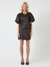 Juodas faktūruotas aprangos komplektas, kurį sudaro dėžutės formos trumpas viršus su pūstomis rankovėmis, sagų detalėmis ir derantis aptemptas sijonas su geometriniu raštu.