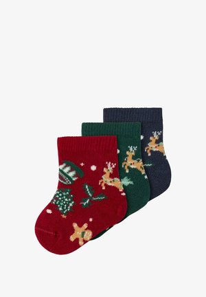 Zestaw trzech skarpetek: czerwone z wzorem reniferów i pierników, zielone z reniferami oraz granatowe z świątecznymi akcentami. Dzianinowa faktura.