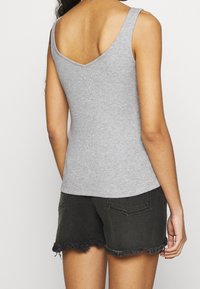 Gray ribbed tank top with a deep V-neck and a fitted design, paired with black denim shorts featuring frayed hem and back pockets.