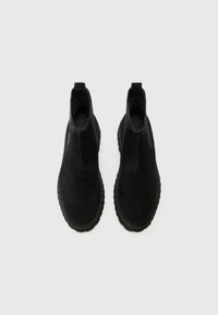 Botines de ante negro con acabado suave, paneles laterales elásticos y suela de goma texturizada. Cuenta con una lengüeta para facilitar su uso.