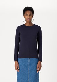 Ναυτικό πουκάμισο μακρύ μανίκι, κατασκευασμένο από υλικό λείο και ελαφρώς ελαστικό. Διαθέτει στρογγυλή λαιμόκοψη και εφαρμοστή σιλουέτα. Συνδυάζεται με τζιν φούστα.