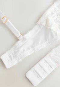 Bralette bianco in pizzo con tessuto a rete, bordi smerlati, spalline regolabili con dettagli in oro e chiusura a gancio con quattro file.