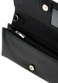 Portafogli nero con tessuto texture, tasca con zip in tono argento, scomparti per schede interni e chiusura a pressione. Superficie liscia e design minimal.