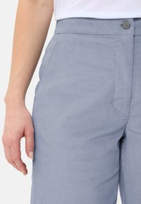 Heledad sinine volditud kantidega püksid, millel on sobiv vöökoht, nööbiga sulgemine, küljetaskud ja tekstuuriga kareda riie.
