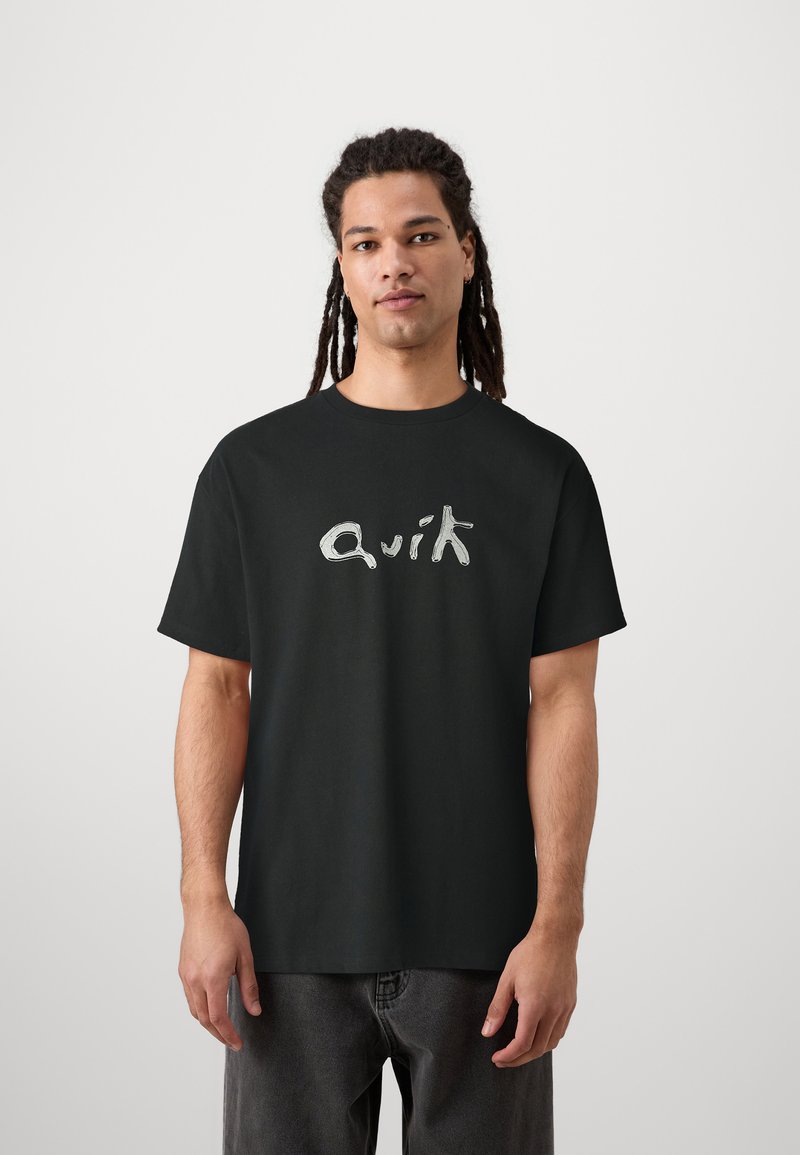 Svart bomulls t-shirt med kort ärm, med en stiliserad vit logotyp "Quik" på framsidan. Enkel design med avslappnad passform.