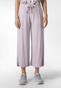 Ljuslila, vida byxor gjorda av mjukt material, med en elastisk midja och snörning. Matchas med grå och lila sneakers.