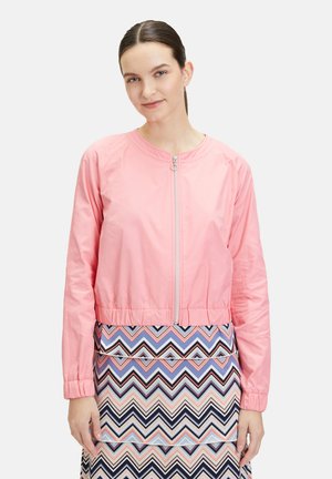 Rosa Bomberjacke aus leichtem Stoff, mit einem Reißverschluss vorne, elastischen Bündchen und einem cropped Schnitt. Kombiniert mit einem gemusterten Rock.