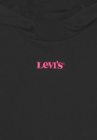 Černá mikina s kapucí, vyrobená z měkkého materiálu a s klokánkovou kapsou. Na hrudi má výšivku růžového loga "Levi's". Kapuce je nastavitelná pomocí šňůrky.