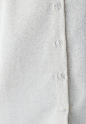 Weißes Leinenhemd mit einer knöpfbaren Vorderseite aus transparenten Kunststoffknöpfen, das einen strukturierten Stoff und ein dezentes, natürliches Erscheinungsbild zeigt.