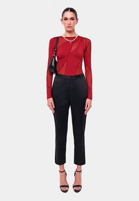 Rød bodystocking med lange ærmer og gennemsigtige paneler, kombineret med sorte skræddersyede bukser. Indeholder blokhælede sandaler og en lille skuldertaske.