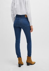 Blå denim skinny jeans med hög midja, med bakfickor och ett märkesläderpatch. Bärs med bruna mocka anklarstövlar.