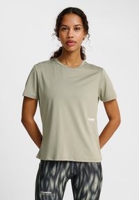 Ljus olivgrön kortärmad tränings t-shirt i texturerad tyg, med en liten vit logotyp på vänster sida.