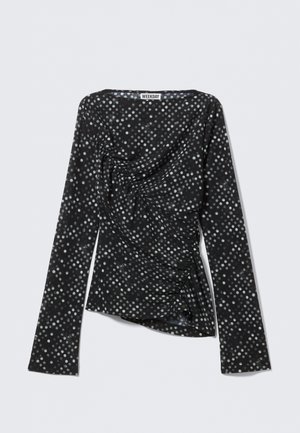 Haut noir à manches longues avec des pois blancs, présentant un design drapé et une texture froncée sur un côté. L'étiquette indique "WEEKDAY."