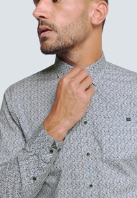 Herrenhemd mit Knopfleiste aus leichtem Stoff, versehen mit einem strukturierten Muster aus blauen und grauen Punkten, mit spitzem Kragen und geknöpften Manschetten.