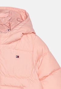 Giacca imbottita rosa chiaro con cappuccio, cuciture a quadretti e piccolo logo rettangolare rosso, bianco e blu sul petto.