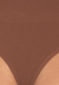 Ropa interior marrón de tiro alto con una tela suave y texturizada, que presenta un diseño sin costuras y bordes redondeados para un ajuste ceñido.