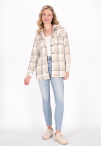 Randig skjorta i beige och vitt, med krage, knappstängning, bröstficka, tillsammans med ljusblå skinny jeans och beige sneakers.