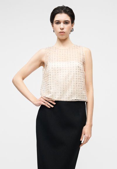 Top sem mangas com contas em tecido translúcido pálido, apresentando um corte quadrado e adornos delicados, combinado com uma saia preta de cintura alta.