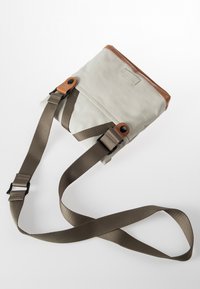 Borsa in tela di un grigio chiaro con dettagli in pelle marrone. Presenta spallacci in tessuto regolabili e una forma rettangolare semplice.