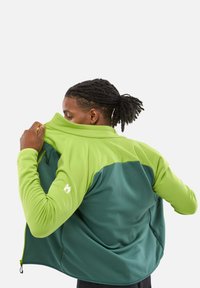Wanderjacke in Grün und Teal, mit einem Reißverschlusskragen, glatter Textur und kontrastierenden Ärmeln. Verfügt über seitliche Taschen.