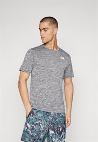 Hallide tekstuuriga lühikeste varrukatega hall T-särk ümmarguse kaelusega ja väikese valge logoga vasakul rinnal. Kantud mitmevärviliste mustritega lühikestega pükstega.