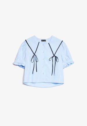 Blusa curta azul clara com mangas curtas bufantes, laços de fita preta na parte da frente, botões semelhantes a pérolas e um colarinho largo.