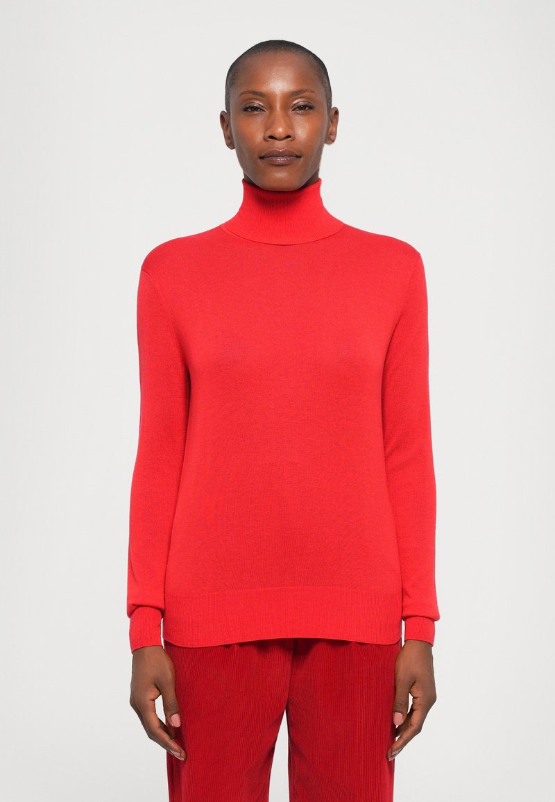 Red turtleneck sweater with long sleeves, ribbed hem, and cuffs; made from a textured knit fabric. Styled with red pants.