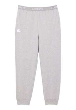 Světlé šedé teplákové kalhoty Lacoste s elastickým pasem, na levém stehně s textem "LACOSTE" a bílým logem krokodýla.