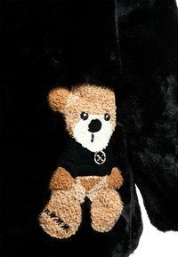 Abrigo de piel sintética negra con un elegante oso de peluche bordado en marrón, vestido con un suéter negro, que muestra detalles texturizados y acentos distintivos.