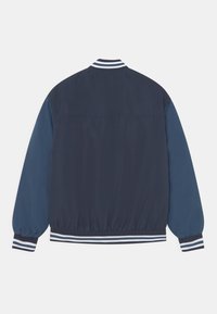 Námořnická lehká bomberská bunda s kontrastními námořnickými rukávy. Hladký límec a manžety s bílými pruhy. Elastický pas s jemnou texturou.