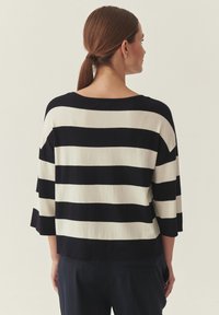 Pull court rayé bleu marine et crème, avec de larges rayures horizontales, un col bateau et des manches trois-quarts. Texture douce.