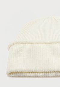 Gorro de punto blanco estriado, textura suave, con puño doblado y parte superior sin costuras. Adecuado para el tiempo frío, diseño versátil para diversos atuendos.