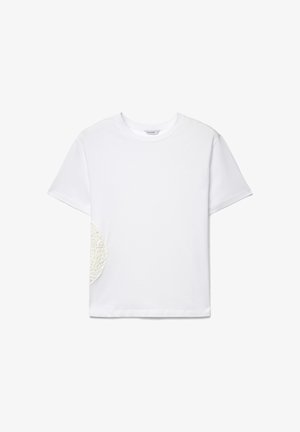 Weißes T-Shirt mit kurzen Ärmeln und Rundhalsausschnitt, mit einem runden, strukturierten Spitzenpatch auf der linken Seite nahe der Taille.
