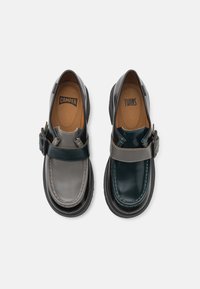 Chaussures en cuir bicolore avec un dessus gris, une bande vert foncé et une semelle noire. Conçues avec un accent de boucle unique.