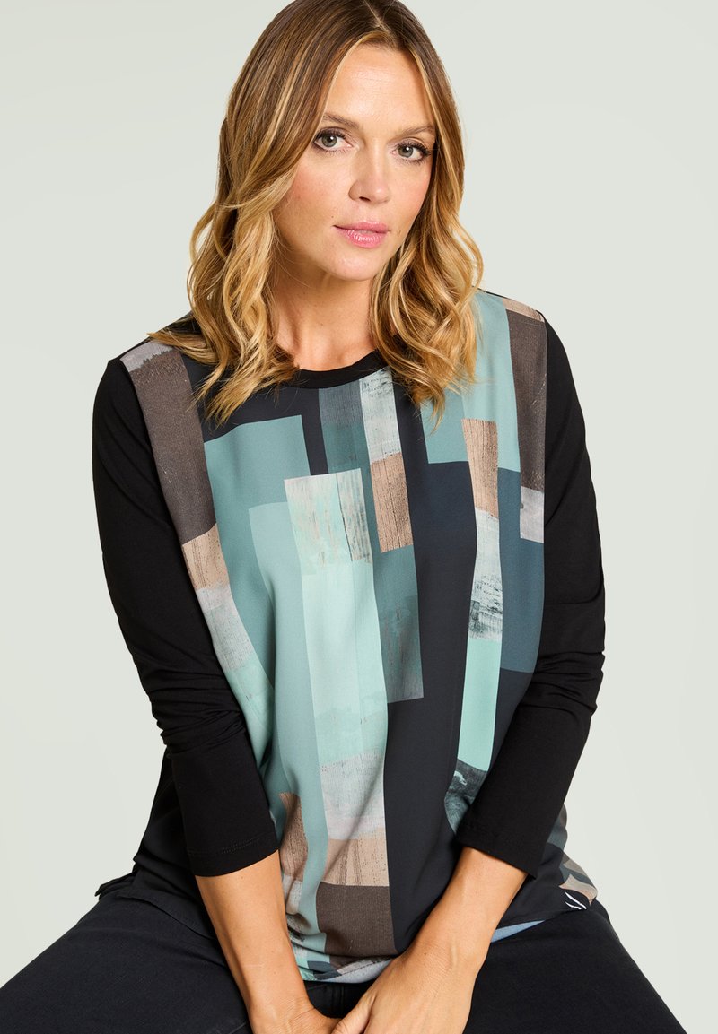Langärmliges Oberteil mit schwarzem Körper und einem geometrischen Muster in Türkis, Beige und Grau auf der Vorderseite, aus glattem Stoff gefertigt.