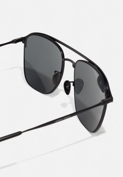 Sunglasses featuring a black metal frame, gray tinted lenses, and a thin, angular design. Includes adjustable nose pads for comfort.