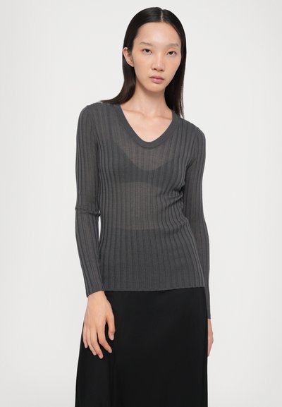 Gray ribbed long-sleeve top with a V-neck design. Soft, sheer texture with vertical lines, paired with a black flowing skirt.
