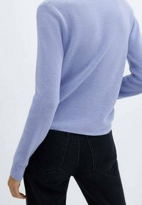 Jasnofioletowy prążkowany sweter z długimi rękawami, o dopasowanym kroju i prostym okrągłym dekolcie, w połączeniu z czarnymi dżinsami.