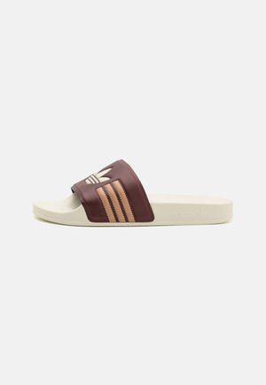 Sandală Adidas tip slide cu un superior sintetic de culoare vișinie, având un logo și trei dungi aurii, așezată pe o talpă texturată de culoare crem.