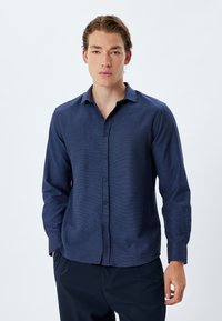Marineblaue, langärmlige Knopfleiste-Hemd mit strukturiertem Muster, klassischem Kragen und Frontleiste mit dunklen Knöpfen.