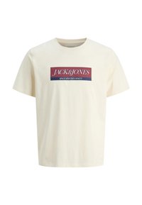 Cremfarbendes T-Shirt mit kurzen Ärmeln aus Baumwolle, das in der Mitte ein rechteckiges Logo-Design in Rot und Blau mit weißen Text zeigt.