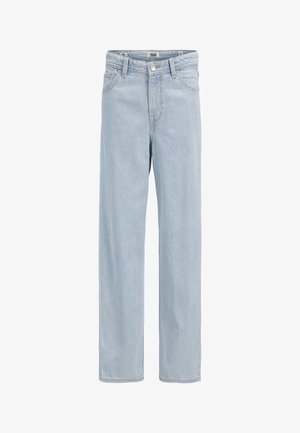 Jasnozielona koszulka z krótkim rękawem z prostokątną czarno-białą grafiką z przodu, w połączeniu z jasnoniebieskimi spodniami szerokimi w nogawkach i szarymi trampkami.