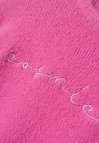 Tessuto di cashmere rosa con una finitura texturizzata, con una discreta scritta ricamata "casmí" in una tonalità più chiara.