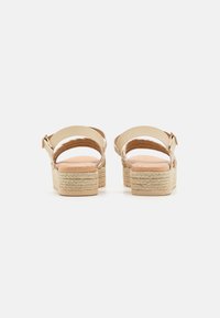 Sandalias de esparto beige con plataforma de cuerda texturizada, correa ajustable en el tobillo y plantilla acolchada, vistas desde atrás.