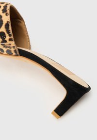 Sandale à talons hauts à motif léopard avec une tige en daim, bout ouvert et un talon en daim noir. Semelle intérieure beige à texture lisse.