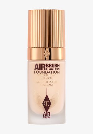 Airbrush Flawless Foundation in a clear glass bottle with a ribbed gold cap. Features elegant typography and decorative accents.