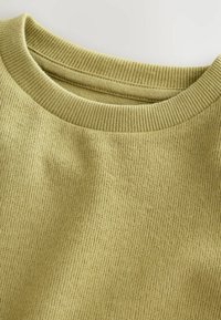 Oliwkowy sweter z fakturowanym, prążkowanym dekoltem i korpusem. Miękka tkanina, charakteryzująca się luźnym krojem i minimalnymi detalami przeszycia.