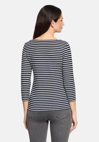 Gestreiftes Langarmoberteil in Marineblau und Weiß mit rundem Ausschnitt, figurbetonter Form und weichem Stoff. Sichtbare Nähte und leichter Stretch.