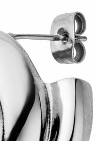 Metallohrringe mit einer glatten, reflektierenden Oberfläche und einem geschwungenen Design. Die Rückseite ist ein kreisförmiger Ring, der an einem dünnen Stift angebracht ist.